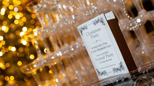 A Christmas party invitation stands in front of a champagne tower